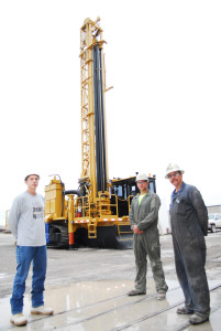 THE NEWEST piece of equipment at Calcite is this Caterpillar drilling rig. Standing in front of it are the men that are going to operate and maintain it. At left is operator Chris Shay. Mechanics Anthony Lafleche and Edward Kania are on the right.  (Photo by Peter Jakey)