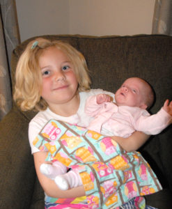 Big sister Ella gets to hold baby sister Cecelia. (Photo by Peter Jakey)