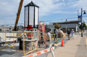 Workers attach the protective casing around the historic Fresnel light at the center of the downtown project in Rogers City. 