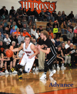 Rogers City's Luke Tulgestke dribbles around Hillman's Billy Kolcan as a big crowd watches the action. (Photo by Richard Lamb)