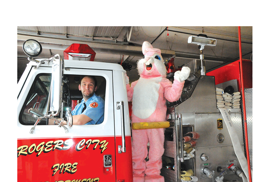 FIREFIGHTER Dylan Ciarkowski drove the fire truck and the Easter Bunny (Chloe Hentkowski) provided the friendly waves along the streets of Rogers City Easter Sunday. The pair saw lots of smiles along the way during their two-hour trek. (Photo by Richard Lamb)