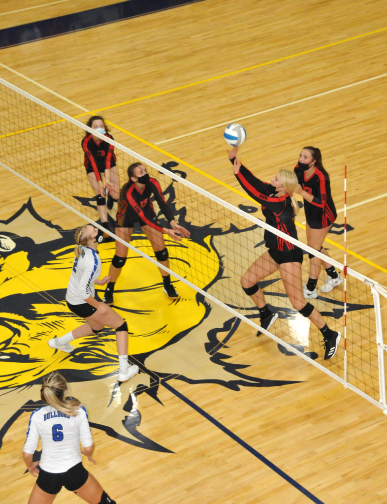 ONAWAY SENIOR Breya Domke tips this ball over to the Inland Lakes side in regional action from Tuesday. Domke and Jazmyn Friant (far left) played in their last match as Cardinals. Other players providing support on the play are sophomore Aubrey Benson (second left) and junior Cloe Ehrke. (Photo by Peter Jakey)