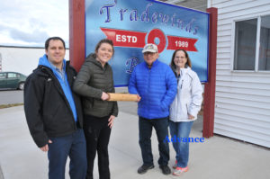 THE PASSING of the rolling pin in front of Tradewinds Bakery last week marked a change of ownership. John Thomas and his wife Carol (right) sold the business to Aaron and Sarah Romel (left). The deal that closed Dec. 3, includes John’s popular fruitcake recipe. It will be business as usual at the start, but expect new services in the new year. (Photo by Peter Jakey)